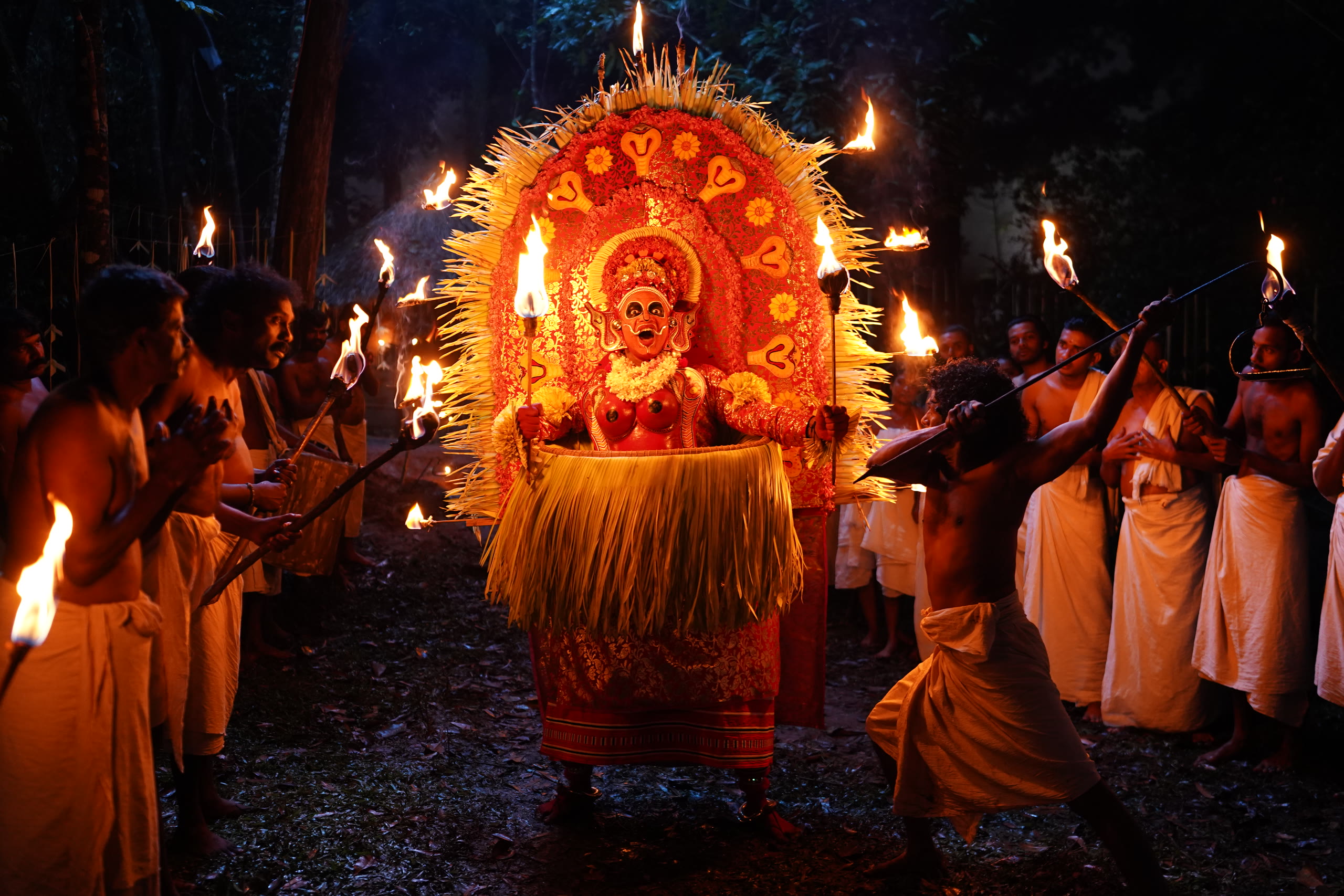 A theyyam performer surrounded by torchbearers during the Vadakkan shoot